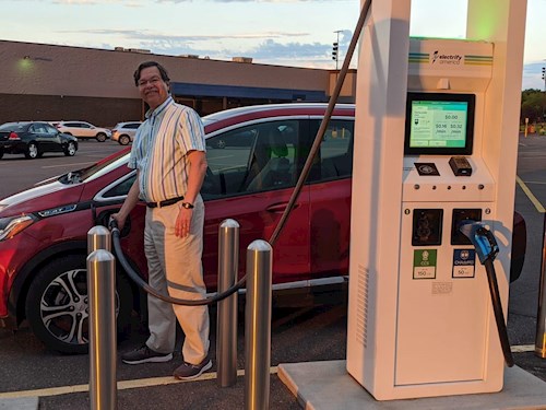 Man plugging electric vehicle into charging station