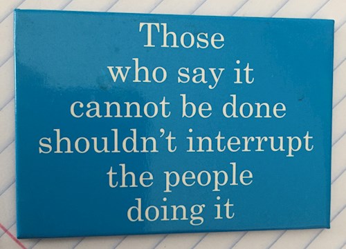 Placard that says Those who say it cannot be done shouldn't interrupt those doing it.