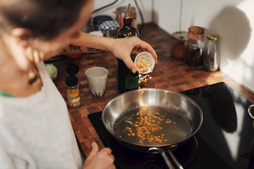 Food is cooked by a person using an induction stovetop in their kitchen.