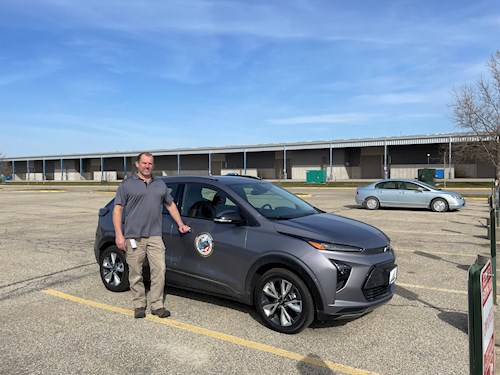 public works director standing in front of grey electric car
