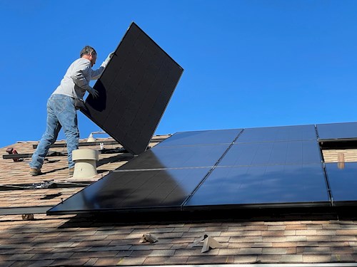 Man installing solar panel on roof