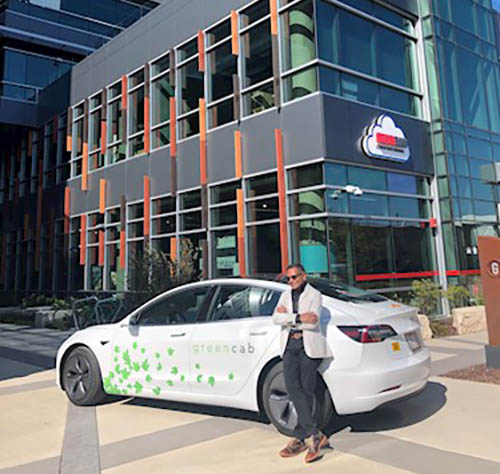 Shree standing in front of a Green Cab Tesla