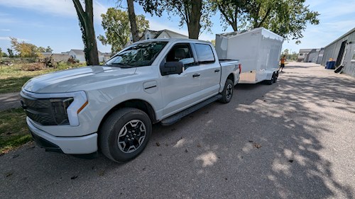 White electric pick up truck towing a trailer